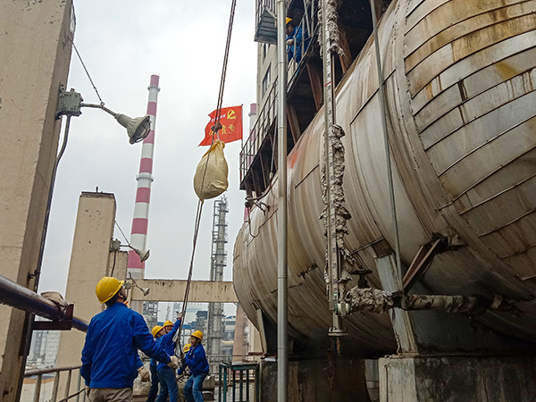 5月10日中午，在動力車間三期工藝除氧器地面，黨員突擊隊(duì)隊(duì)員用滑輪往工藝除氧器平臺運(yùn)送鋼絲網(wǎng)，用以纏繞新填料.jpg