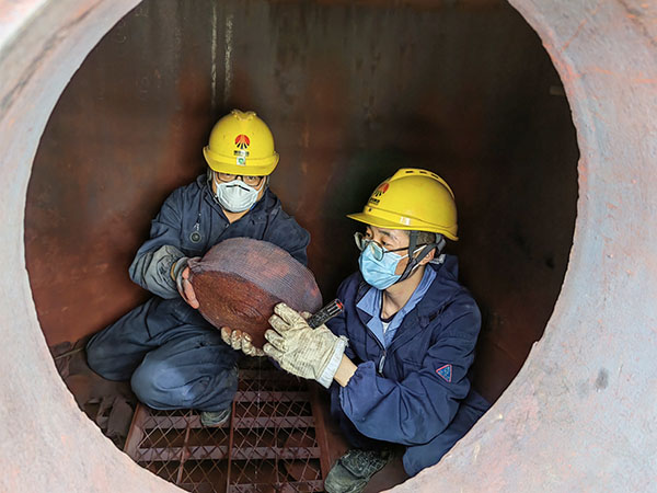 5月11日，動(dòng)力車間三期工藝除氧器內(nèi)部，黨員突擊隊(duì)隊(duì)員劉瑞斌和李震正在清理舊填料.jpg